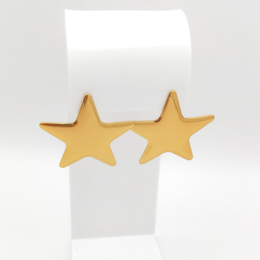 A pair of gold star-shaped stud earrings displayed on a white jewelry stand against a clean white background.