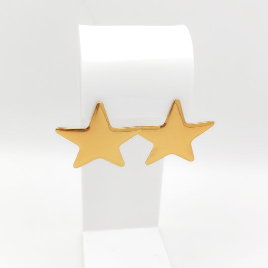 Pair of high-polish gold-plated stainless steel star stud earrings displayed on a white stand.