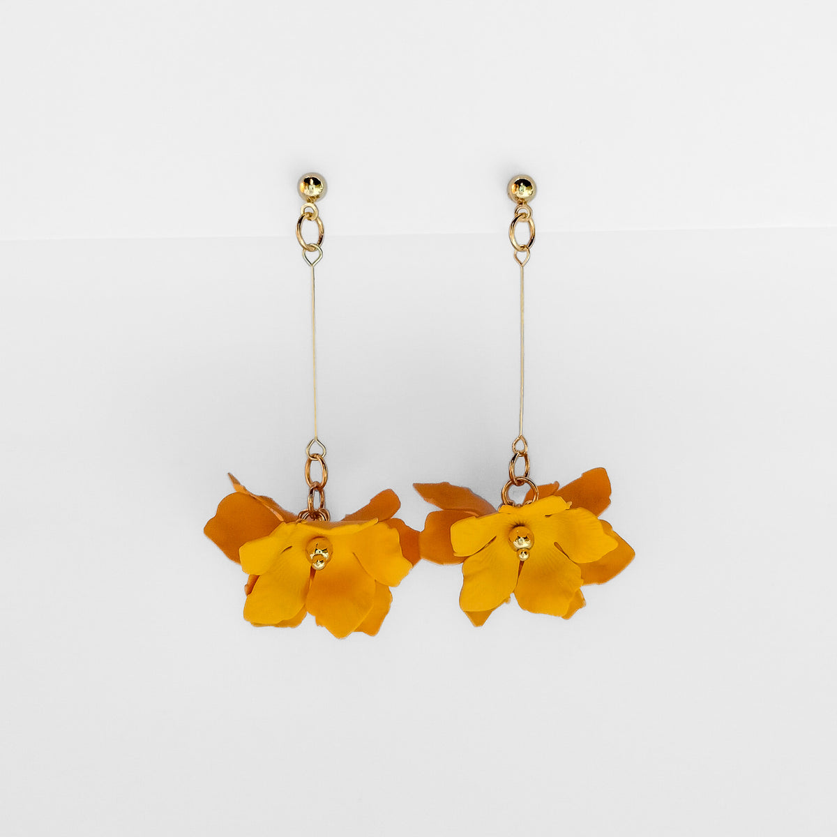 gold plated yellow flower dangle earrings on a white display stand