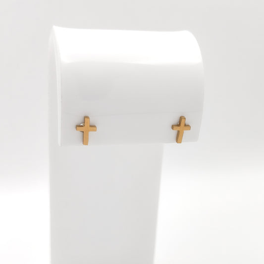Pair of gold-plated cross stud earrings on a white display stand.