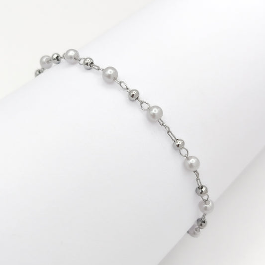 Close-up of white pearl beads alternating with silver-tone beads along a silver-plated bracelet chain.