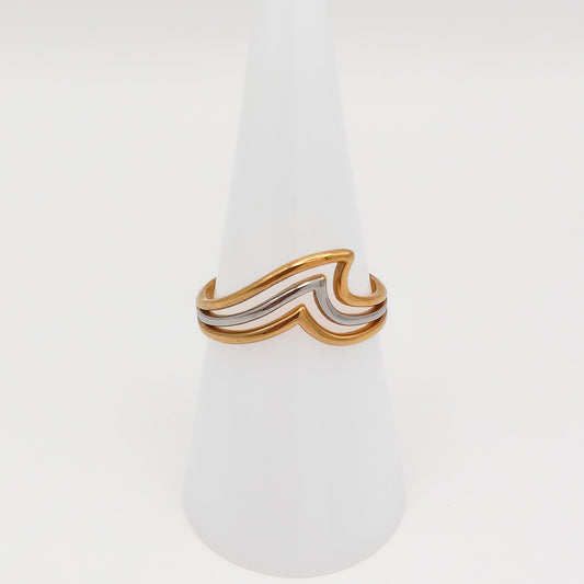 Mixed-metal adjustable stainless steel ring with a layered gold and silver wave design, displayed on a white cone stand.