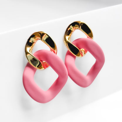 pink and gold plated chain dangle earrings on a white display