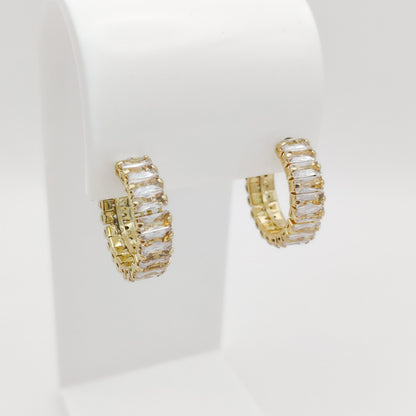 A pair of 22mm gold plated hoop earrings with baguette-cut clear crystals, displayed on a white jewelry stand against a white background.
