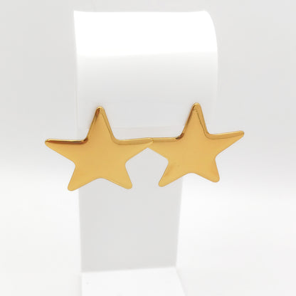 A pair of gold star-shaped stud earrings displayed on a white jewelry stand against a clean white background.