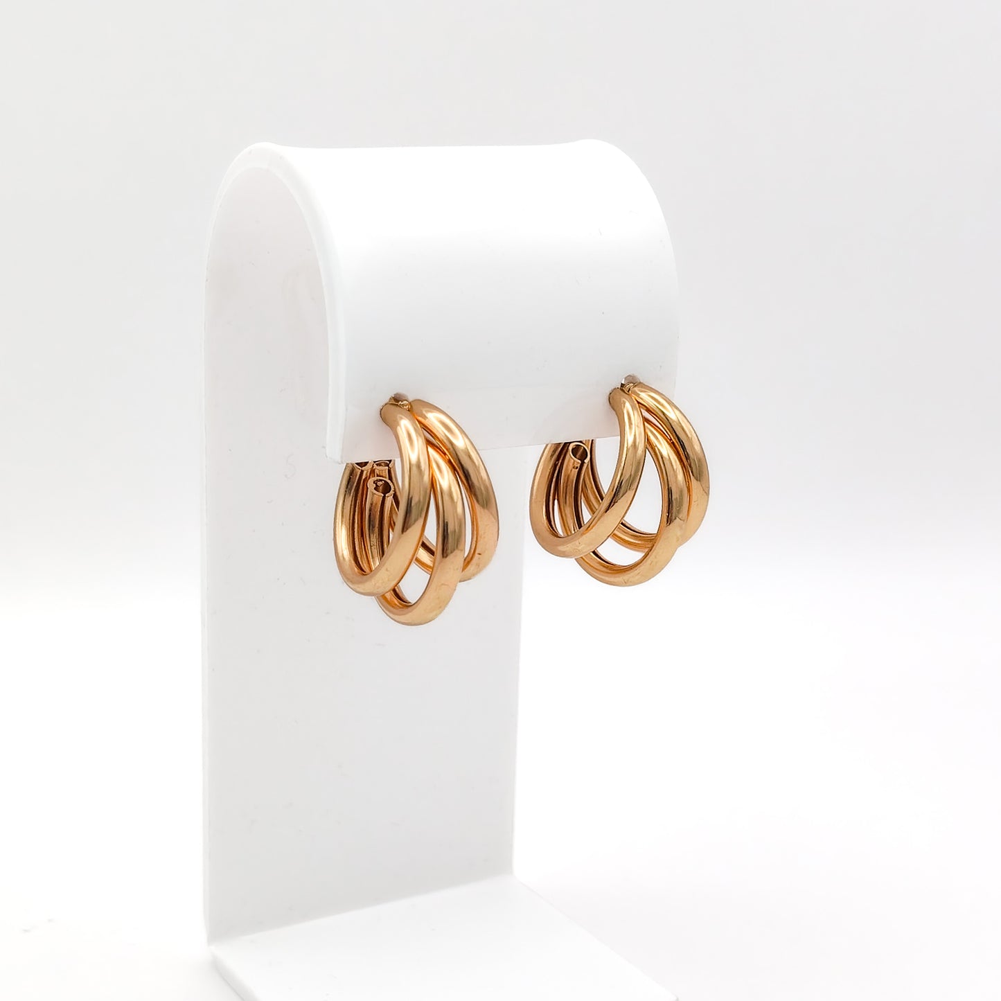 Pair of gold hoop earrings on a white display stand
