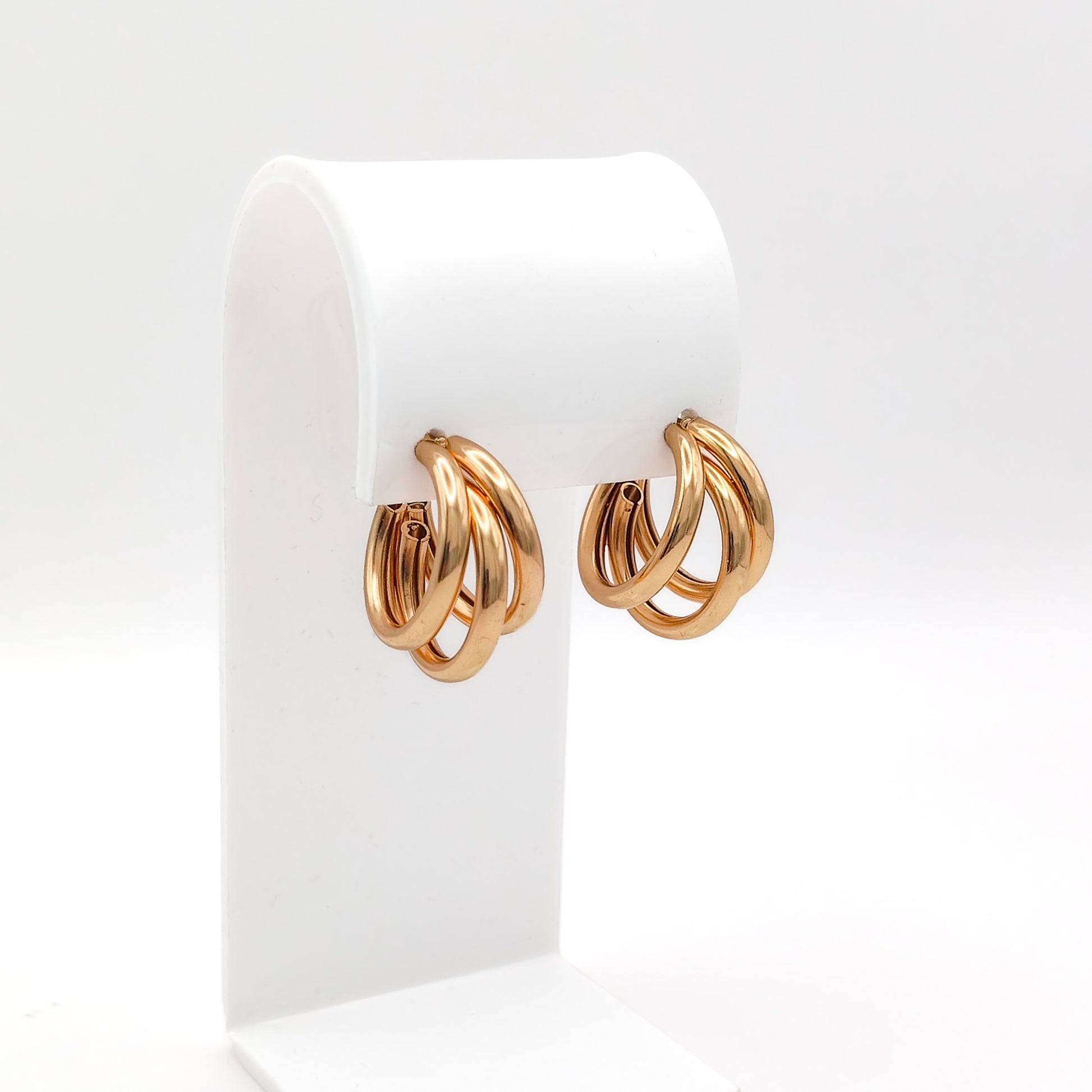Pair of gold hoop earrings on a white display stand