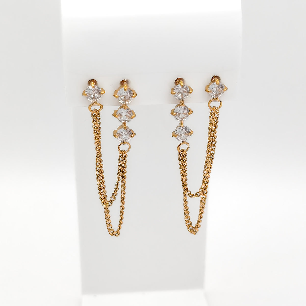Front view of gold-plated double-hole chain earrings with clear cubic zirconia studs on a white stand.