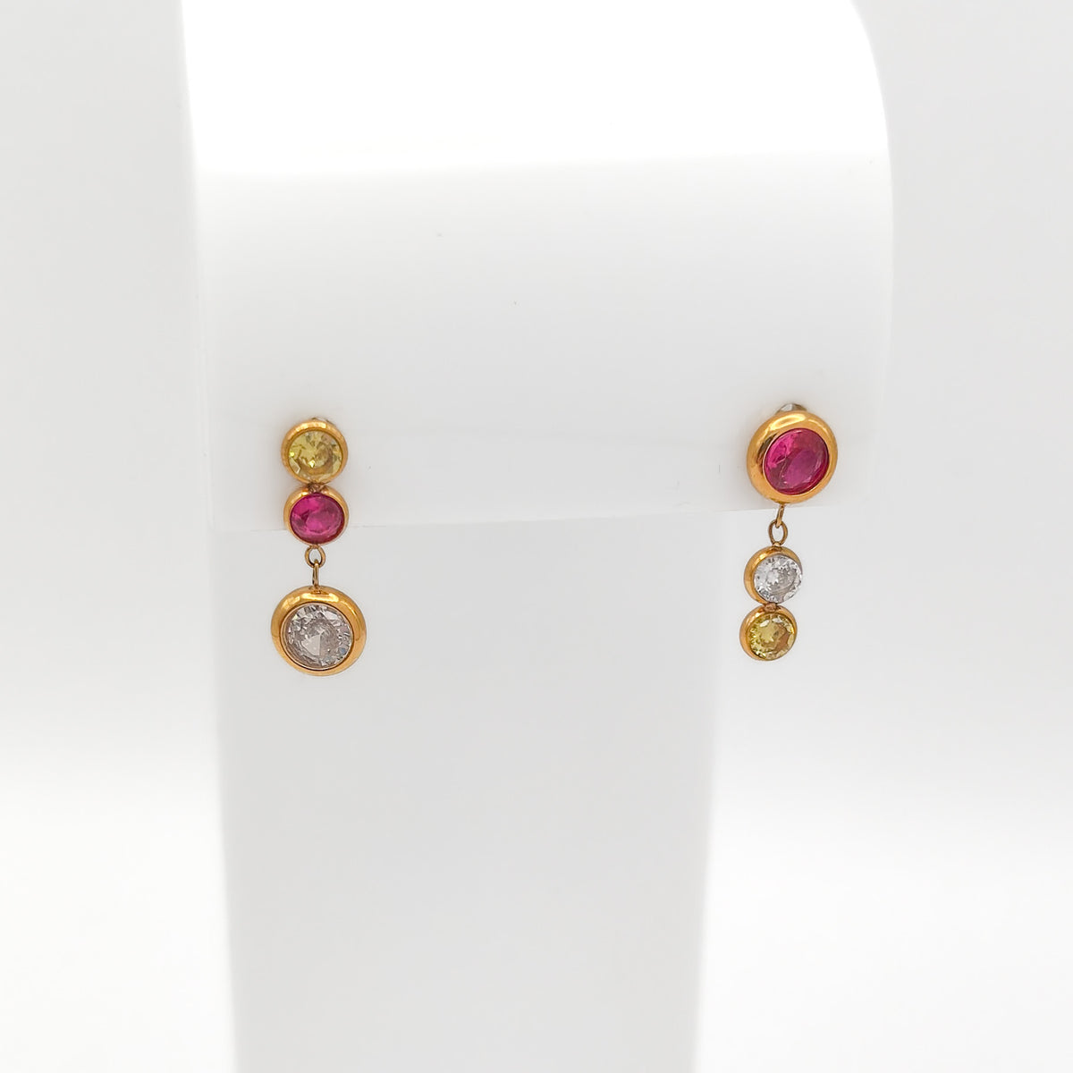 Front view of gold-plated stainless steel drop earrings featuring bezel-set round pink, yellow, and clear CZ gems on a white stand.