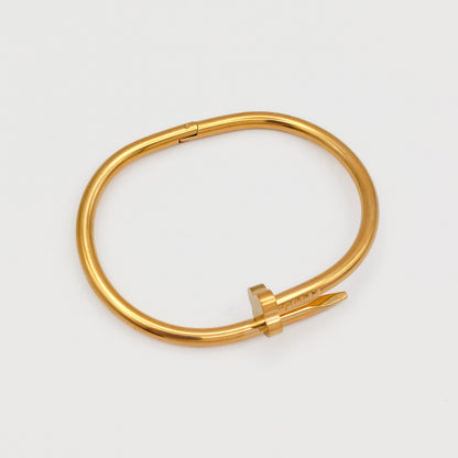 Flat lay view of the closed gold plated nail hinge bangle, showcasing its precise 6.0cm oval contour and tarnish-free stainless steel design.