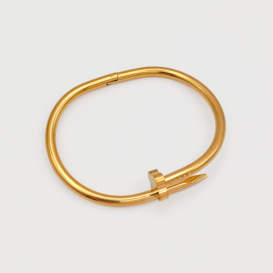 Flat lay view of the closed gold plated nail hinge bangle, showcasing its precise 6.0cm oval contour and tarnish-free stainless steel design.