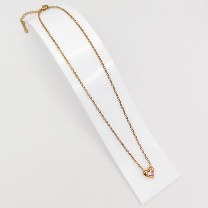 Delicate gold-plated stainless steel chain necklace with a petite heart pendant featuring a sparkling pink cubic zirconia stone, showcased on a white display stand.