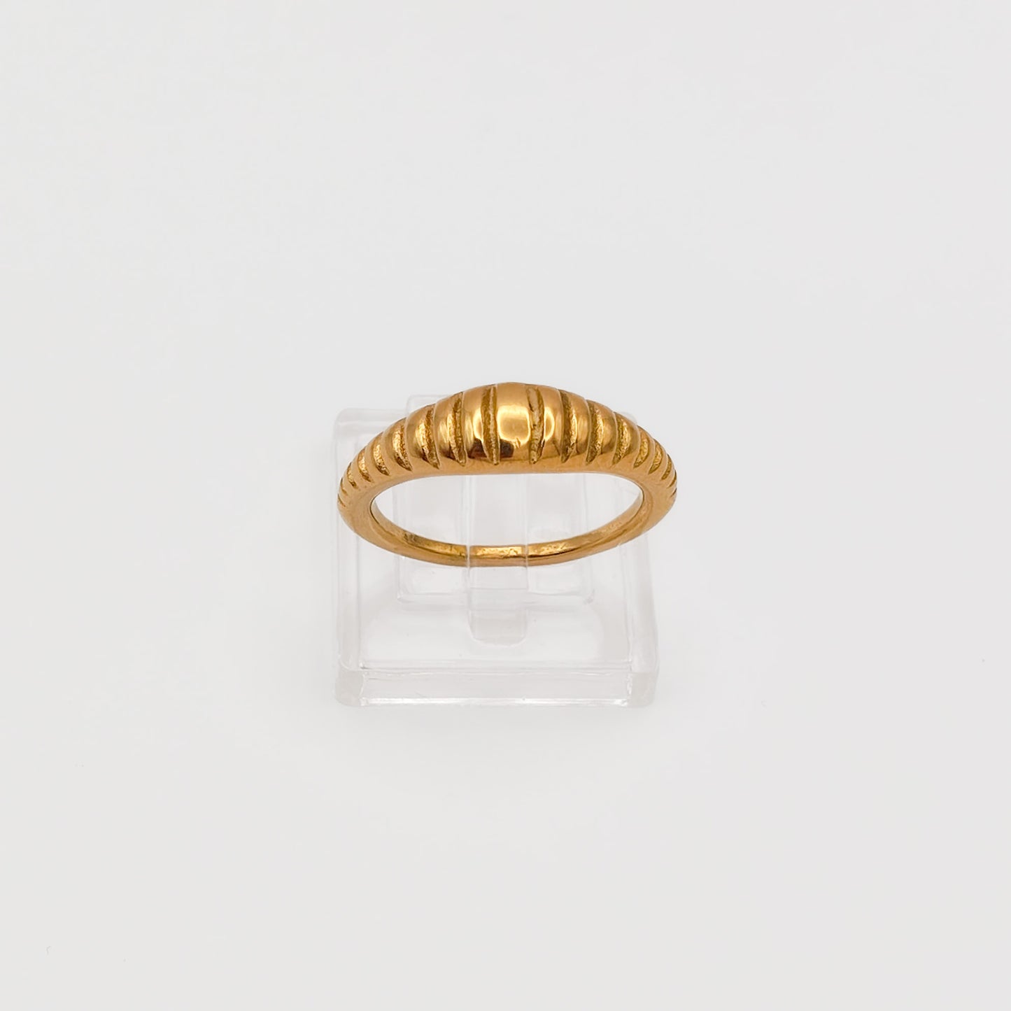 Close-up of the gold-plated ribbed dome ring on a clear acrylic stand, showcasing the polished vertical ridges.