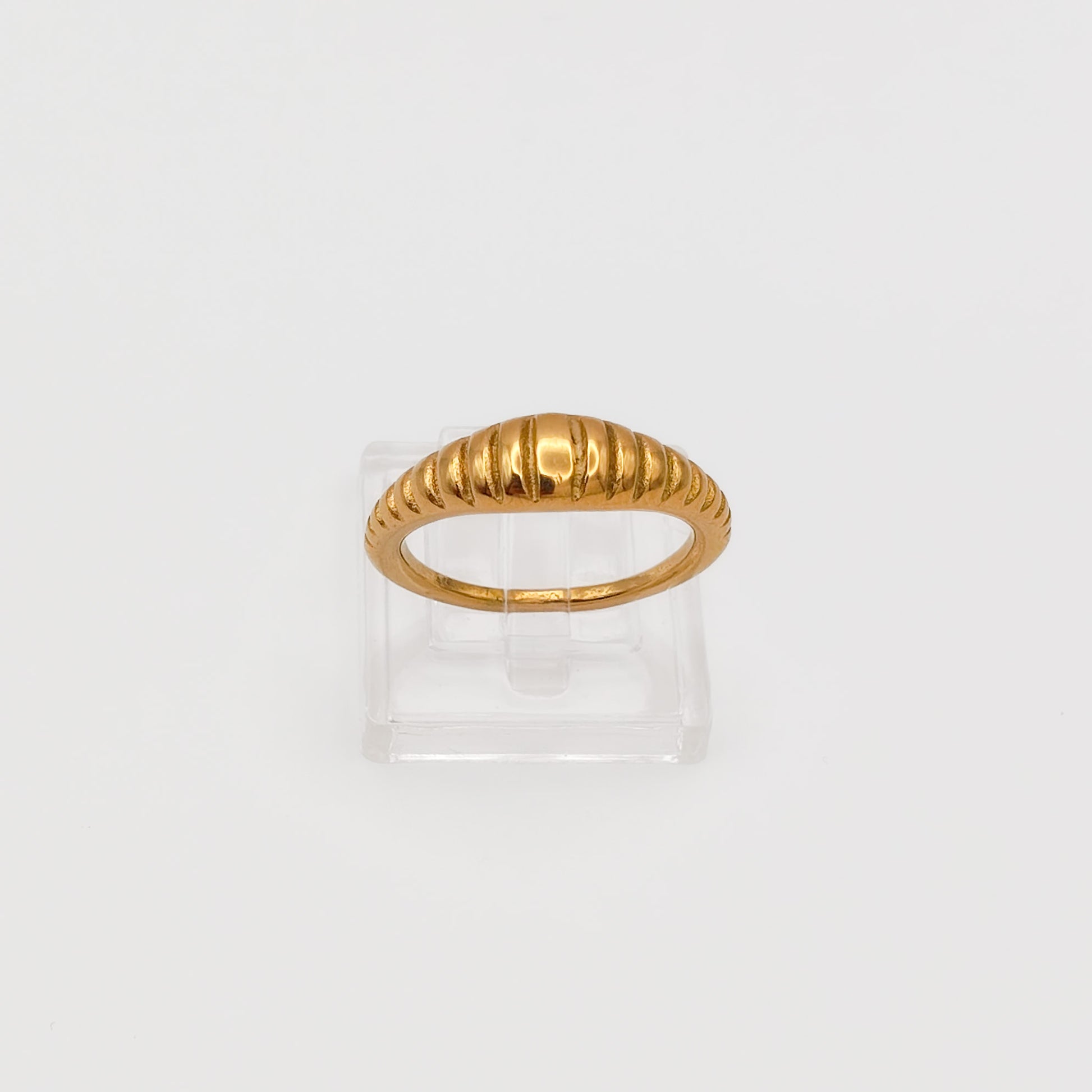 Close-up of the gold-plated ribbed dome ring on a clear acrylic stand, showcasing the polished vertical ridges.