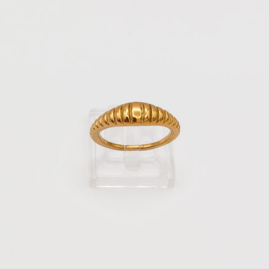 Close-up of the gold-plated ribbed dome ring on a clear acrylic stand, showcasing the polished vertical ridges.