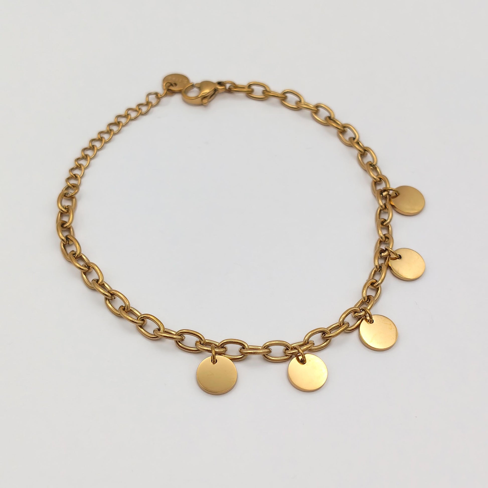packshot of a gold plated round disk bracelet that is waterproof and tarnish resistant