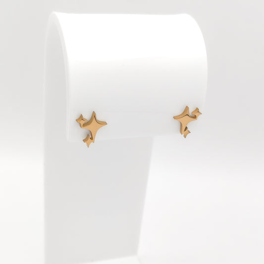 A pair of gold-plated stainless steel starburst sparkle stud earrings featuring a multi-point celestial cluster motif, displayed on a white stand.