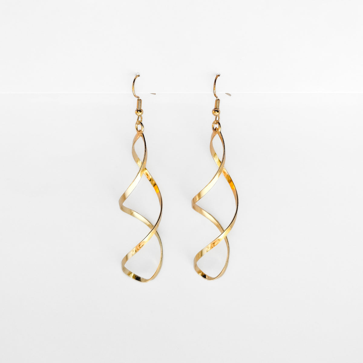 gold plated spiral dangle earrings hanging on a white display
