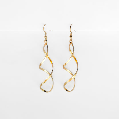 gold plated spiral dangle earrings hanging on a white display