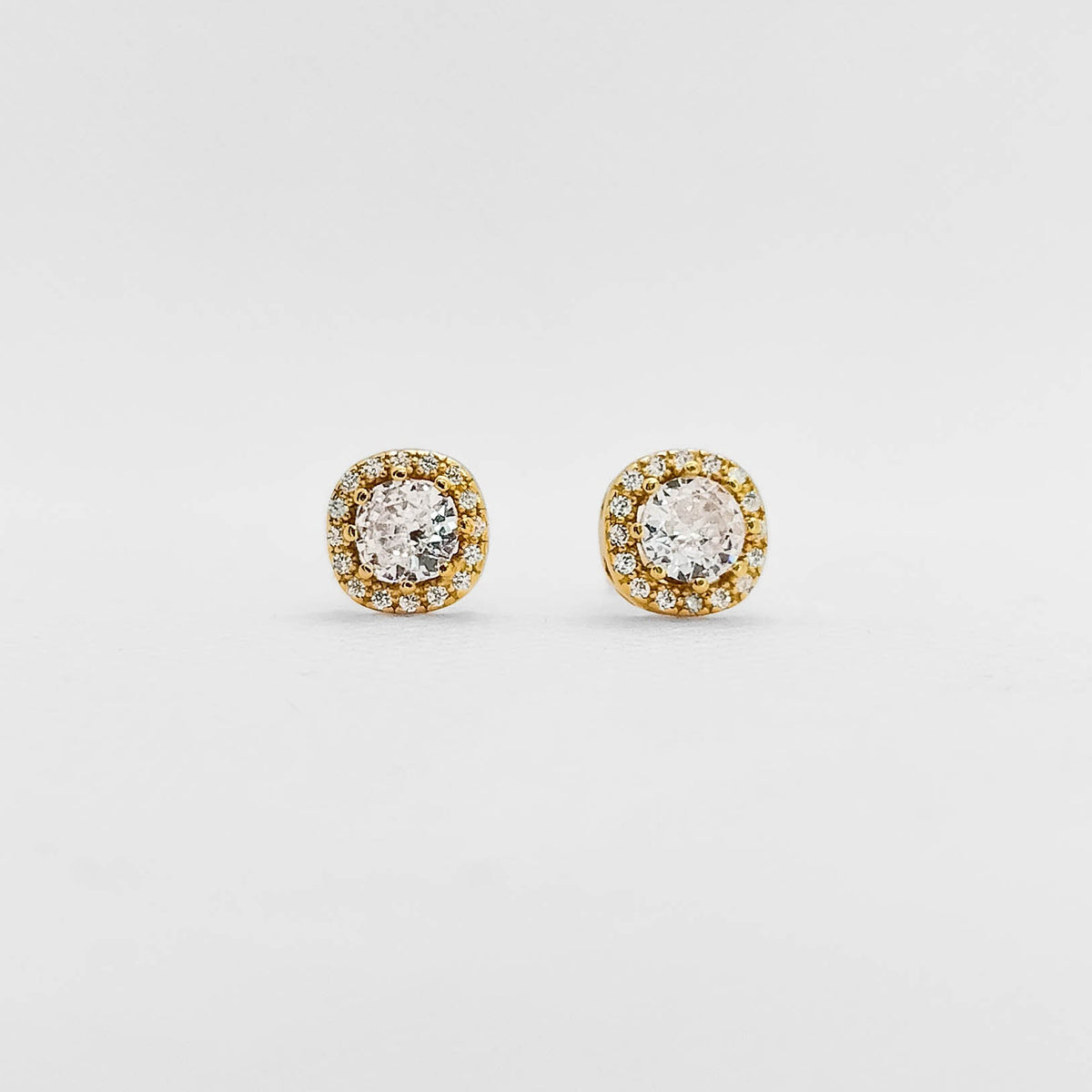 A pair of round stud earrings with clear central stones surrounded by a halo of small yellow gold stones on a plain light gray background.