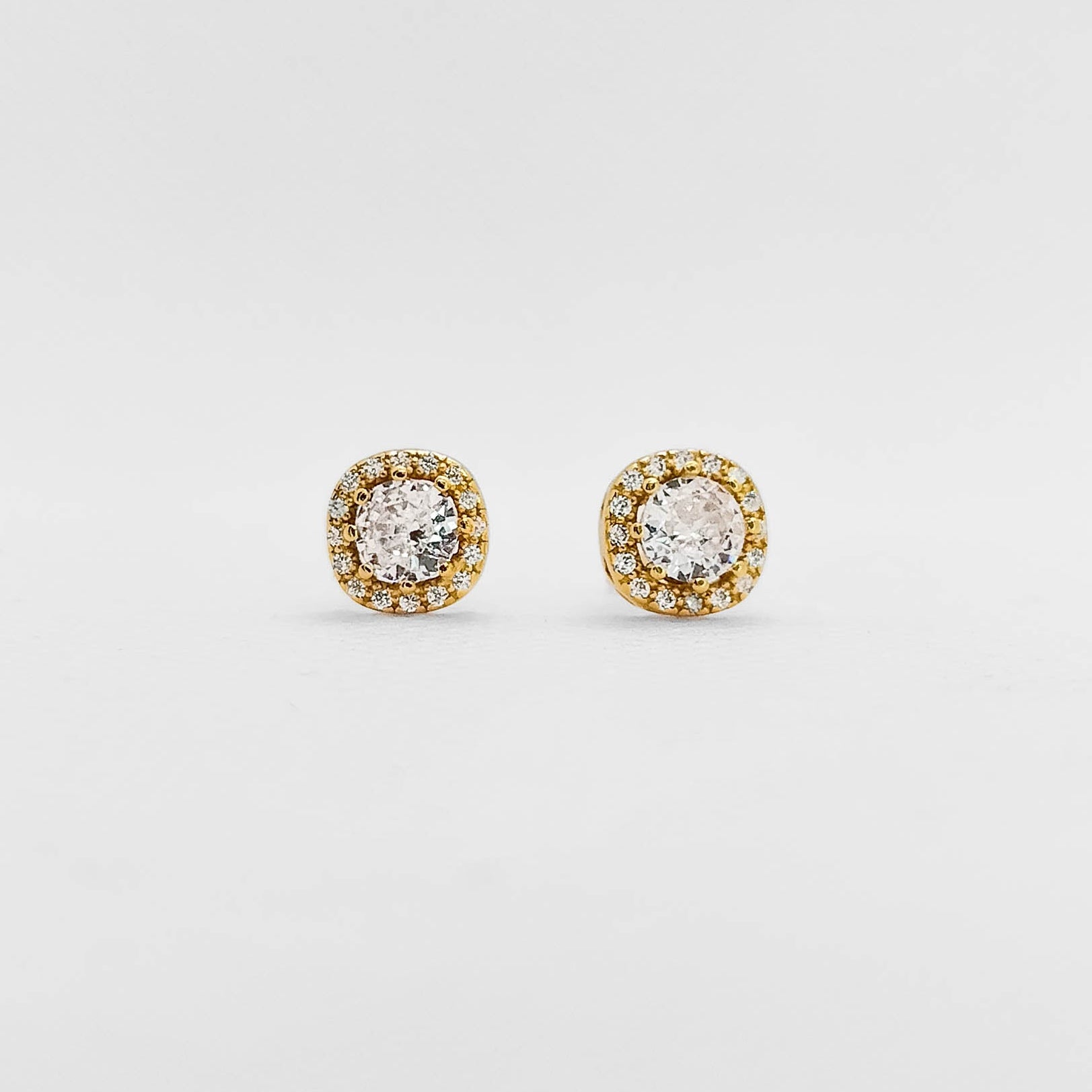 A pair of round stud earrings with clear central stones surrounded by a halo of small yellow gold stones on a plain light gray background.