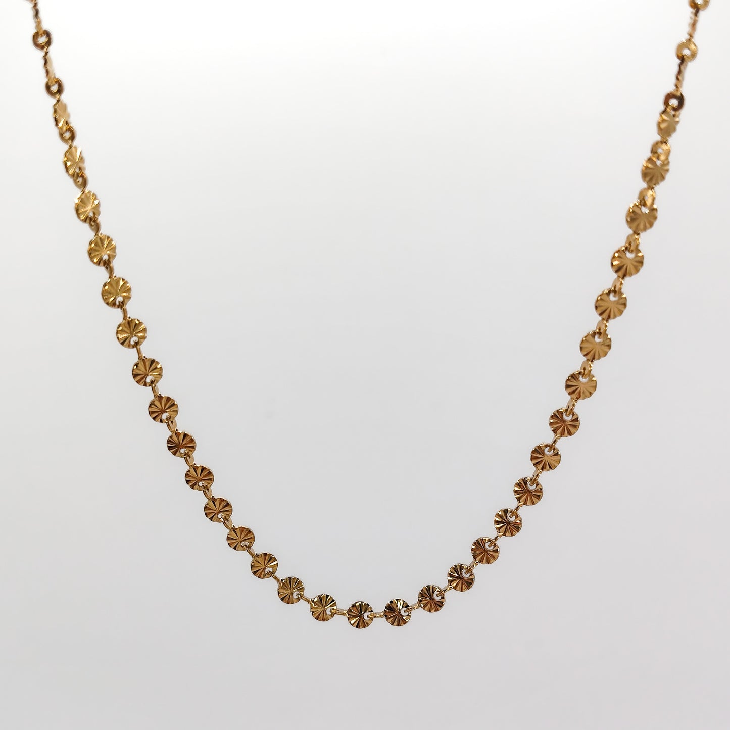 A close-up view of the gold-plated chain, showcasing the intricate diamond-cut ridges radiating from the center of each 4mm disc link.