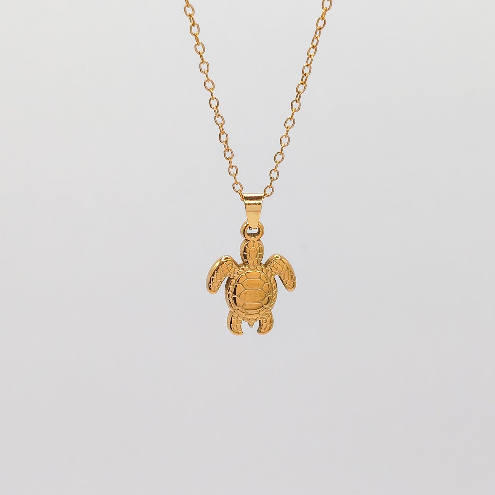 packshot of a gold plated sea turtle pendant necklace that is waterproof and tarnish resistant