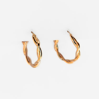 gold plated twisted hoop earrings hanging on a white display