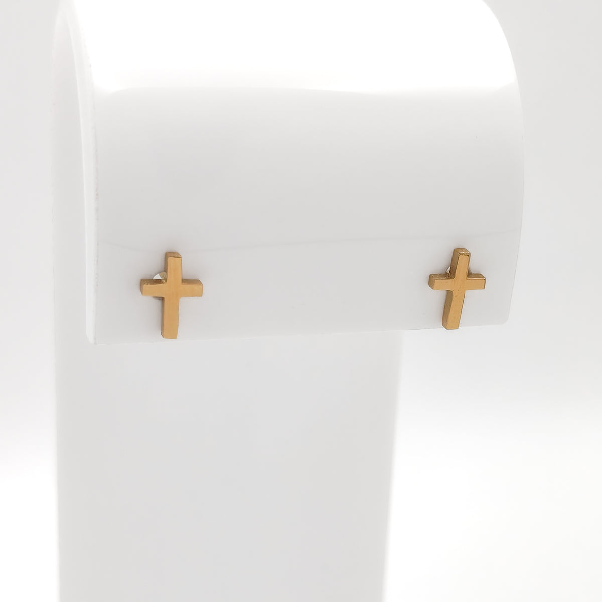 Close-up of gold-plated cross stud earrings showing the simple cross design.