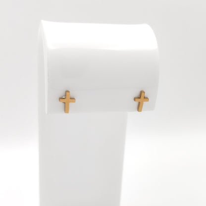 Pair of gold-plated cross stud earrings on a white display stand.