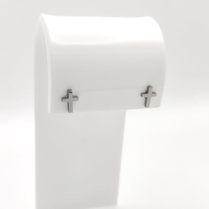 Pair of silver-plated cross stud earrings on a white display stand.