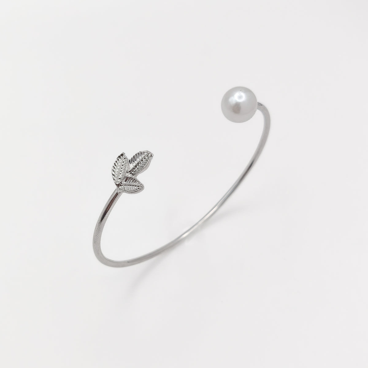 Silver-plated open cuff bangle with a three-leaf detail and white pearl bead on opposite ends.