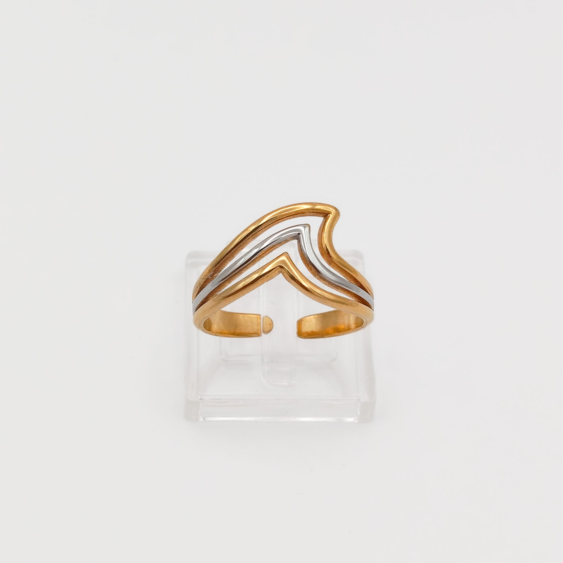 Front view of the gold and silver layered chevron wave ring on a clear acrylic stand, showcasing the open-back adjustable band.