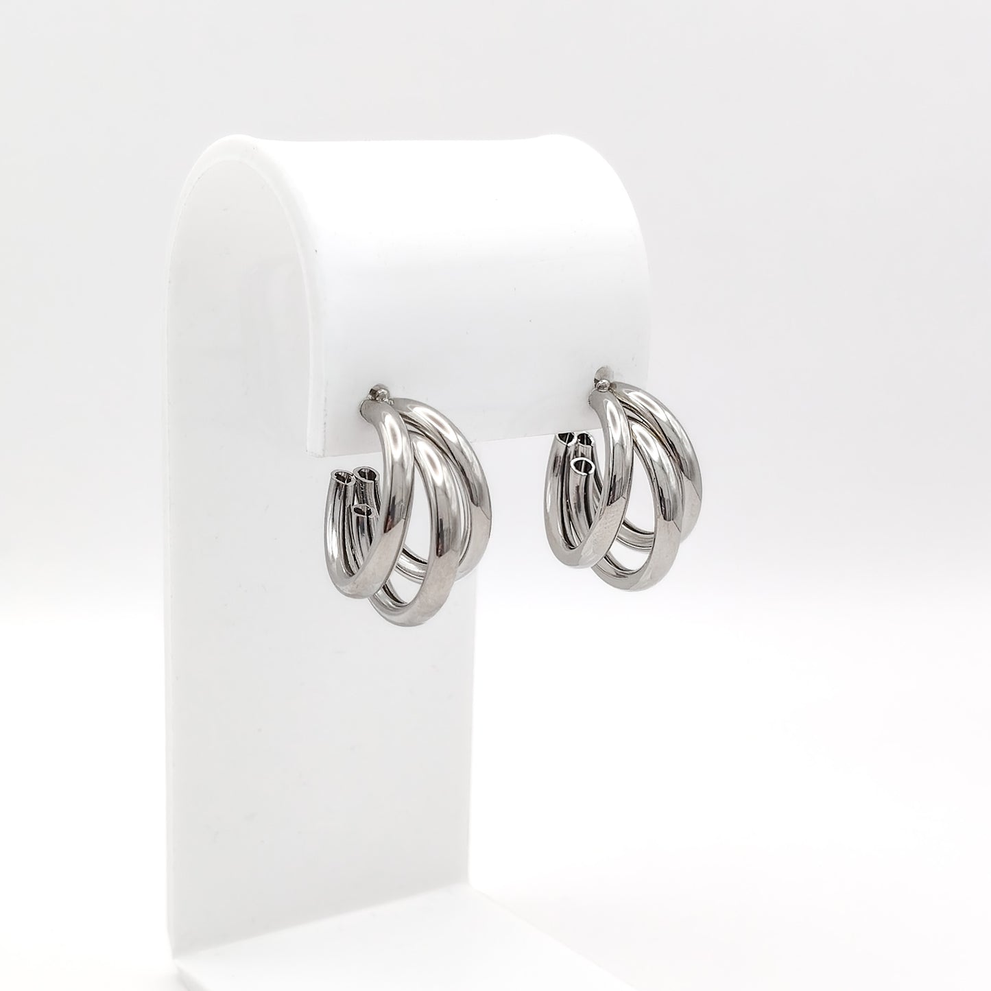 Pair of silver hoop earrings on a white display stand