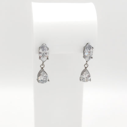 A pair of silver-tone drop earrings with marquise-cut and pear-cut clear gemstones, displayed on a white jewelry stand against a white background.