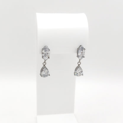 A pair of silver-tone drop earrings with marquise-cut and teardrop-cut clear gemstones, displayed on a white jewelry stand against a white background.