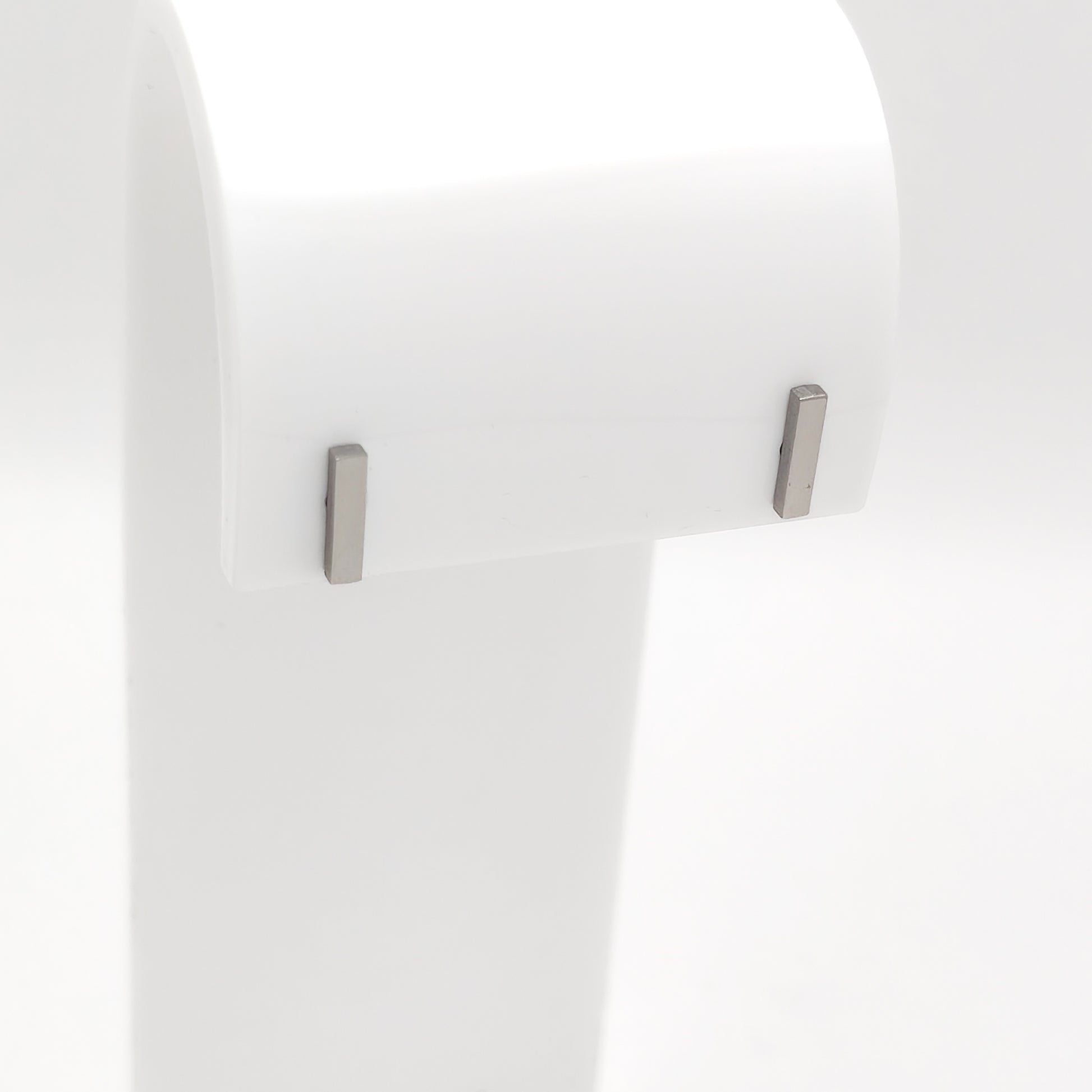 Detailed close-up of a pair of silver-plated stainless steel minimalist vertical bar stud earrings with a sleek geometric profile, displayed on a white stand.