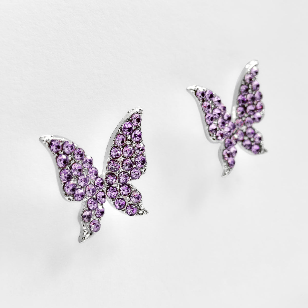 image of silver plated butterfly stud earrings with purple rhinestones on a white background